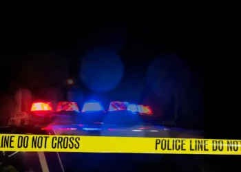 Police car with flashing lights behind "Police Line Do Not Cross" tape, representing a Saint Lucia shooting update and crime scene investigation.