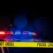 Police car with flashing lights behind "Police Line Do Not Cross" tape, representing a Saint Lucia shooting update and crime scene investigation.