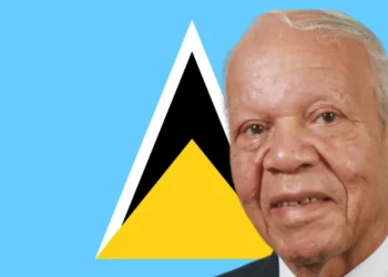 Sir John Compton standing proudly in front of the Saint Lucia flag, symbolizing the Sir John Compton Legacy and his dedication to the nation