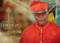 Cardinal Kelvin Felix in his church attire, standing with a serene expression, wearing his traditional red cassock and biretta, symbolizing his esteemed position in the Catholic Church.