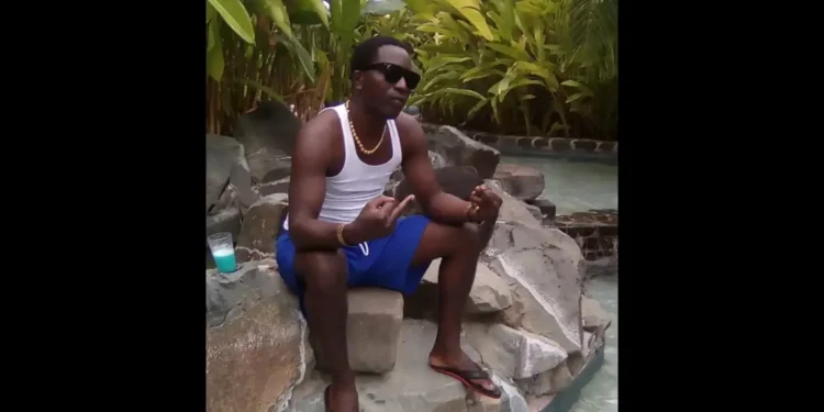 Devon Maximin in a white vest raising his middle fingers, victim of a Saint Lucia targeted shooting