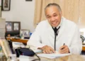 Dr. Martin Didier, a distinguished Saint Lucian medical professional, smiling and seated at his desk in a white lab coat, showcasing his commitment to healthcare.
