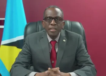 Philip J. Pierre speaks during the third anniversary of his party, against a dirty red background, highlighting the St. Lucia Healthcare Crisis