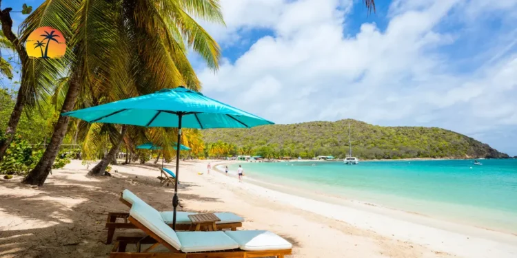 Tourists leisurely strolling on a white sand beach, enjoying the beautiful sunshine at the Caribbean Tourism Conference 2024 in the Cayman Islands.