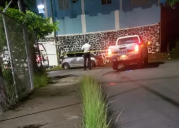 Saint Lucia ex-cop shooting crime scene with police vehicle, yellow tape, and officer standing guard amidst rising crime under Philip J. Pierre’s watch