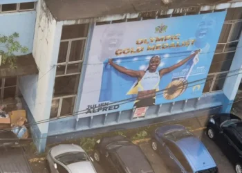 Shocking Saint Lucia billboard of Olympic gold medalist Julien Alfred on a dilapidated building, reflecting neglect and poor governance.
