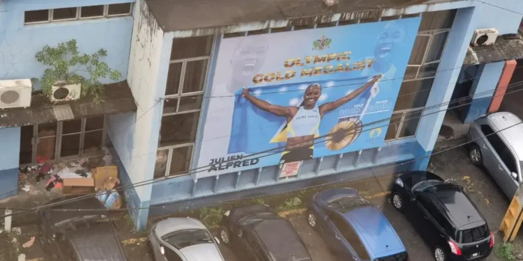 Shocking Saint Lucia billboard of Olympic gold medalist Julien Alfred on a dilapidated building, reflecting neglect and poor governance.