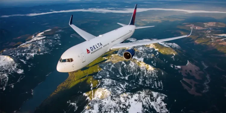 A Delta airplane flying over snow-capped mountains and valleys, illustrating the story of a stowaway on a Delta flight to Paris.