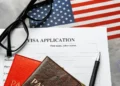 A US visa application form with a pen, passport, glasses, and an American flag, representing the US Visa Waiver Program process.