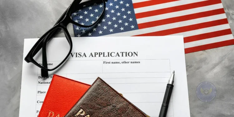 A US visa application form with a pen, passport, glasses, and an American flag, representing the US Visa Waiver Program process.
