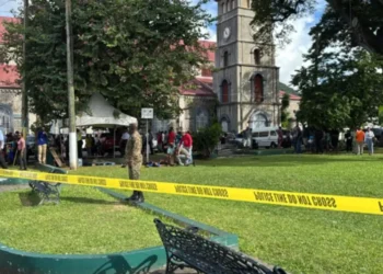 Crime scene at Derek Walcott Square shooting in Castries, showing police tape cordoning off the area with bystanders and law enforcement present.