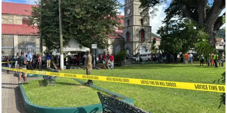 Crime scene at Derek Walcott Square shooting in Castries, showing police tape cordoning off the area with bystanders and law enforcement present.