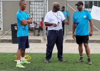 Emmanuel Bellas, legendary Vieux Fort football coach, in a white shirt during a coaching session, sharing his expertise and leadership.