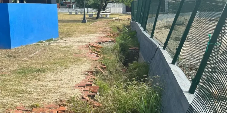 Crumbling Gros Islet park infrastructure with damaged walls and overgrown vegetation, highlighting construction flaws.
