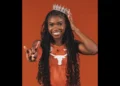 Naomi London in Texas Longhorns uniform, smiling with a crown and hand gesture.