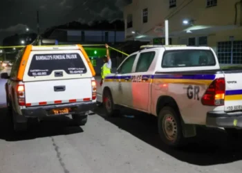 Police vehicles and a funeral hearse at the scene of the Corinth Armed Robber Shot incident in Saint Lucia during a late-night investigation.