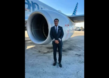 Tevin Belasco, a St. Lucian pilot, standing confidently in front of an American Airlines aircraft, celebrating his historic milestone.