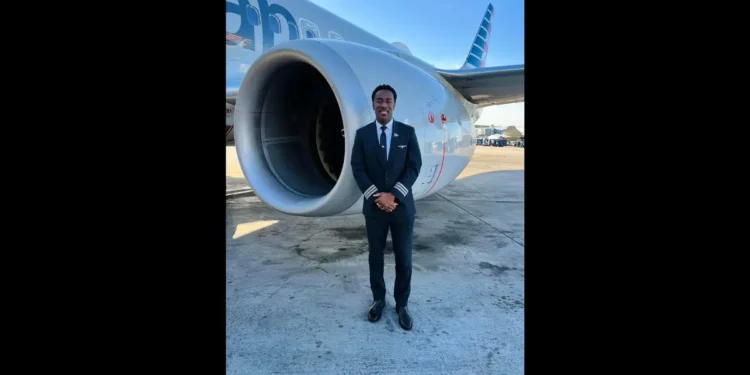 Tevin Belasco, a St. Lucian pilot, standing confidently in front of an American Airlines aircraft, celebrating his historic milestone.