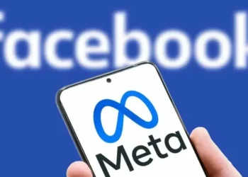 A smartphone displaying the Meta logo with a blurred Facebook logo in the background, symbolizing the Meta policy shift toward free expression and community-driven moderation.