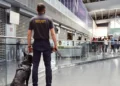 Back view of a security officer with a police dog at an airport terminal, representing enhanced safety measures and 2025 travel requirements.