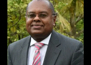 Dr. James Fletcher, a distinguished St. Lucian climate advocate and CARICOM Climate Envoy, pictured in a formal suit outdoors.