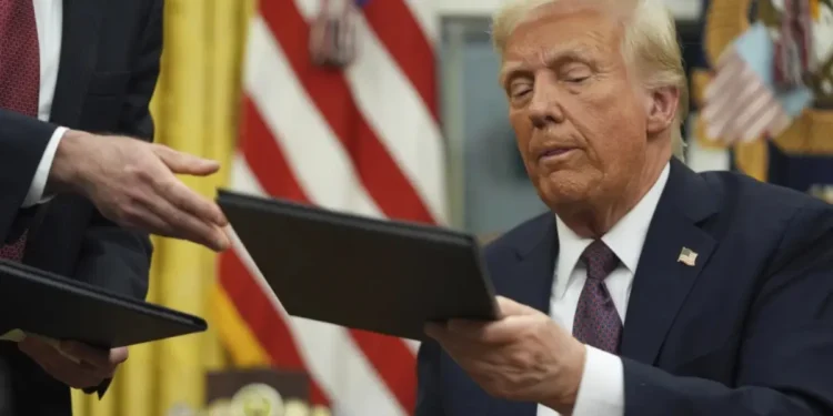 President Donald Trump signs an executive order in the Oval Office on January 20, 2025, halting foreign aid funding. (AP Photo/Evan Vucci)