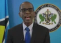 St Lucia PM Philip Pierre speaking in front of the Office of the Prime Minister emblem and Saint Lucia flag