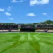 A 2018 vibrant view of the Daren Sammy Cricket Ground in Saint Lucia under clear blue skies, showcasing the stadium's lush green outfield and iconic stands.