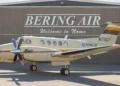 A Bering Air Cessna 208B Grand Caravan parked in front of a hangar with Welcome to Nome signage. The aircraft is similar to the missing Alaska plane carrying 10 people.