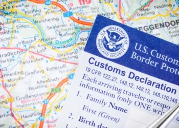 A U.S. Customs and Border Protection customs declaration form placed over a map, representing immigration enforcement as the Trump administration mandates alien registration.
