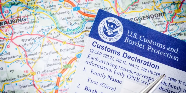 A U.S. Customs and Border Protection customs declaration form placed over a map, representing immigration enforcement as the Trump administration mandates alien registration.