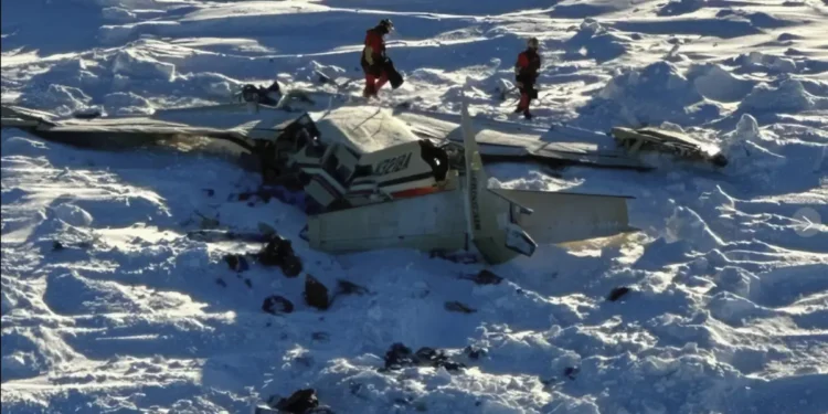 Wreckage of the Alaska plane found on sea ice near Nome, showing debris scattered across snowy terrain as U.S. Coast Guard rescue workers assess the crash site.