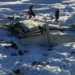 Wreckage of the Alaska plane found on sea ice near Nome, showing debris scattered across snowy terrain as U.S. Coast Guard rescue workers assess the crash site.