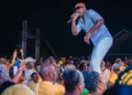 Officer Kakal performing on stage at a UWP event in Dennery, engaging with a large crowd dressed in yellow.