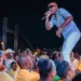 Officer Kakal performing on stage at a UWP event in Dennery, engaging with a large crowd dressed in yellow.