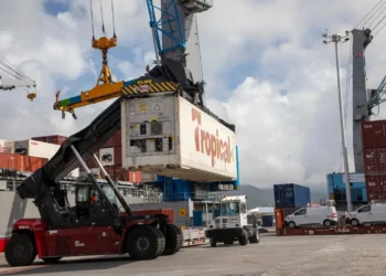 Tropical Shipping container being loaded at a Caribbean port, highlighting how US tariffs could cripple Caribbean trade.