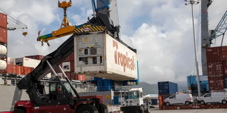 Tropical Shipping container being loaded at a Caribbean port, highlighting how US tariffs could cripple Caribbean trade.