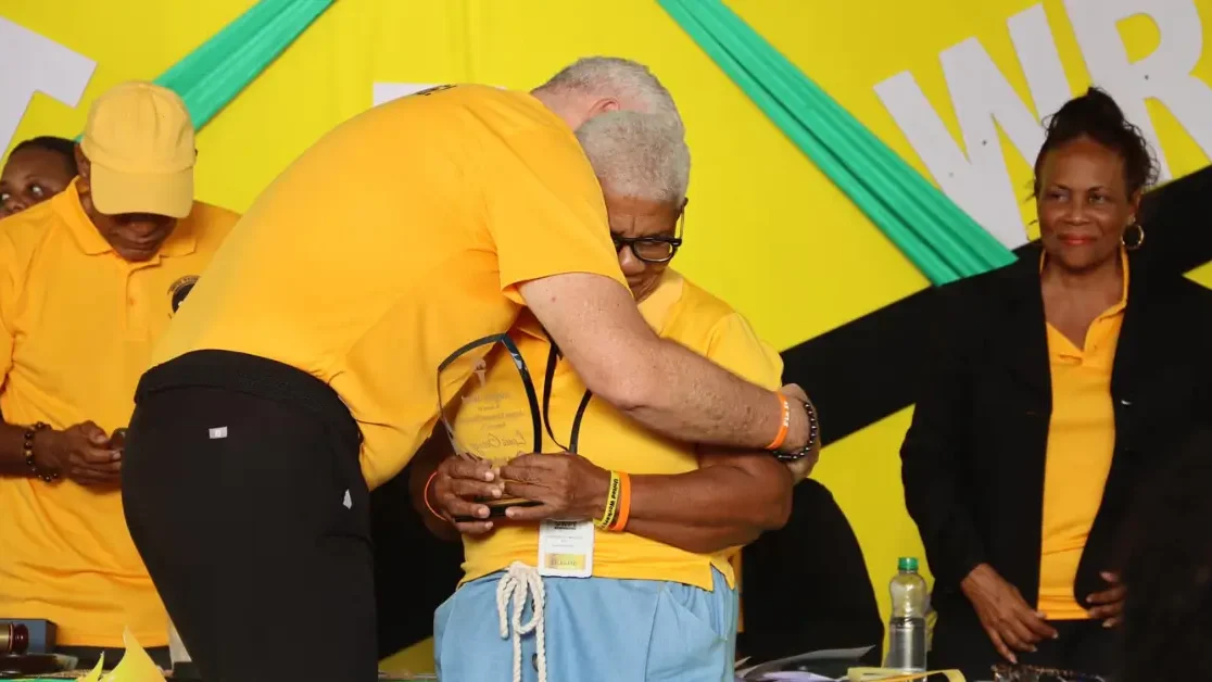 Hon. Allen Chastanet embraces Mrs. George while presenting the Louis George Award