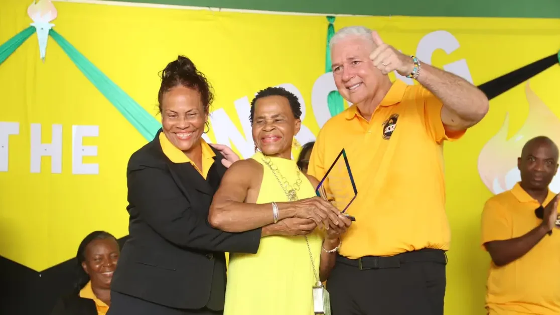 Hon. Allen Chastanet, alongside the UWP General Secretary, presents an award to Mrs. James from Micoud South