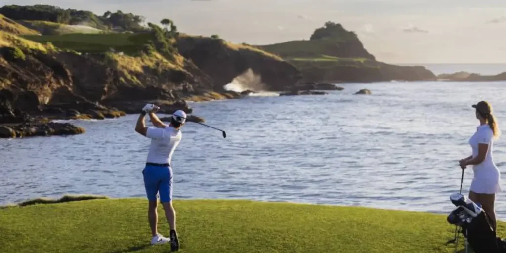Golfer tees off at Point Hardy Golf Club, Cabot St Lucia, with dramatic ocean cliffs in the background.