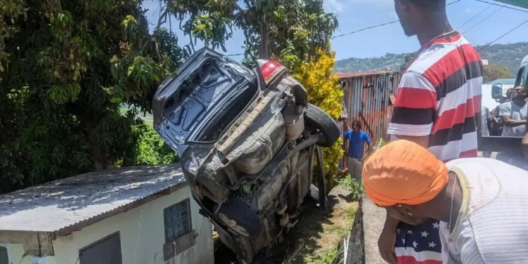Bystanders gather at the scene after vehicle crashes into home at Barre Denis