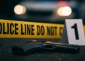 Dennery shooting spree scene with police tape, handgun, and evidence marker after Kennedy Leon’s fatal shooting.