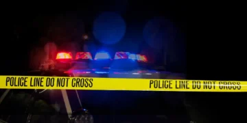 Stock image of police car with flashing lights and crime scene tape used to illustrate RSLPF Castries Operation amid gun violence crackdown.