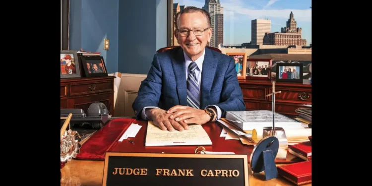 Judge Frank Caprio dies at 88, former Providence Municipal Court chief smiling at his office desk with nameplate and family photos.