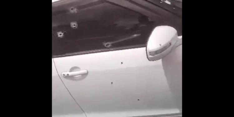 Bullet-riddled white car targeted in Marchand daylight gun attack, showing multiple bullet holes on the door and window