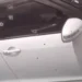 Bullet-riddled white car targeted in Marchand daylight gun attack, showing multiple bullet holes on the door and window