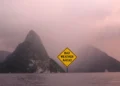 Graphic illustration of the Pitons in St Lucia under stormy skies with a sign reading Bad Weather Ahead for the St Lucia weather August 24 2025 update.
