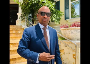 Stephen Fevrier, wearing a blue suit and sunglasses, stands outside a building in Castries after delivering his Stephen Fevrier crime statement on August 19, 2025