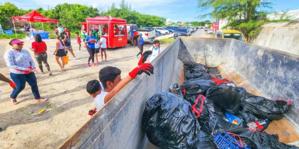 Volunteers at the Blue Lagoon Island coastal cleanup load bags of debris into a dumpster at Yamacraw Beach in The Bahamas.