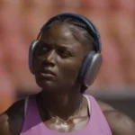 Julien Alfred road to Tokyo captured in focus as she prepares on the track wearing headphones and training gear.